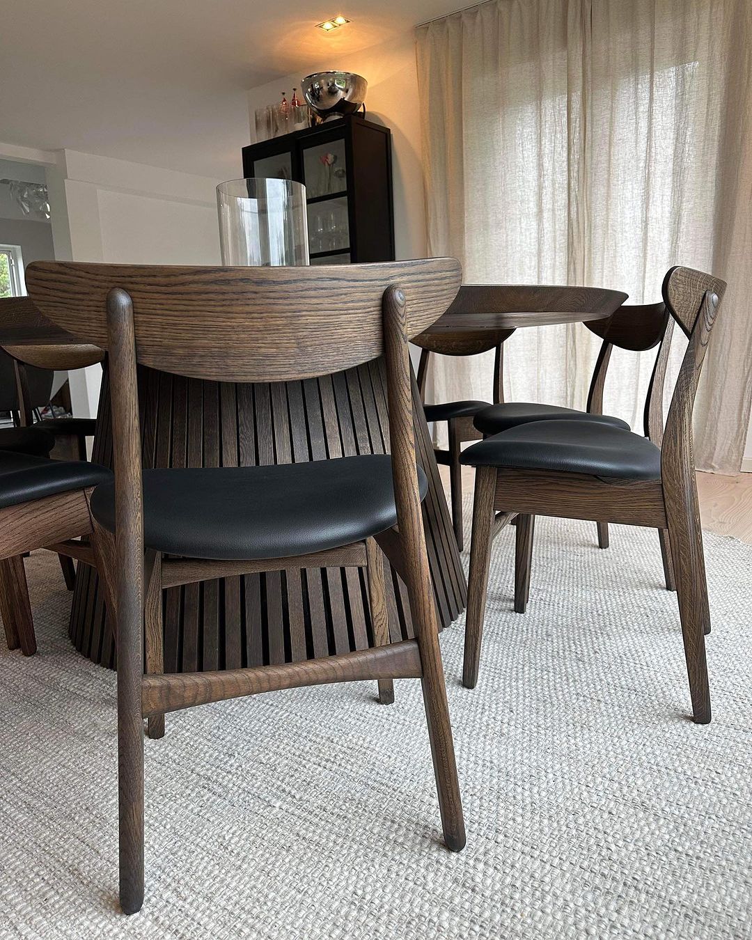 Round extendable solid wood dining table with wood pipe legs in dark oak.