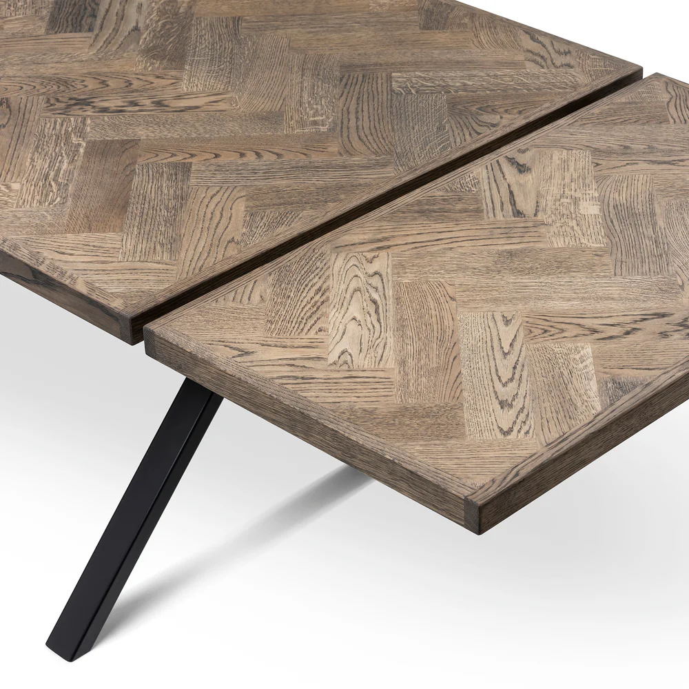 Gaia herringbone solid wood extendable dining table in charcoal oak with cross metal legs – luxury solid wood furniture piece.