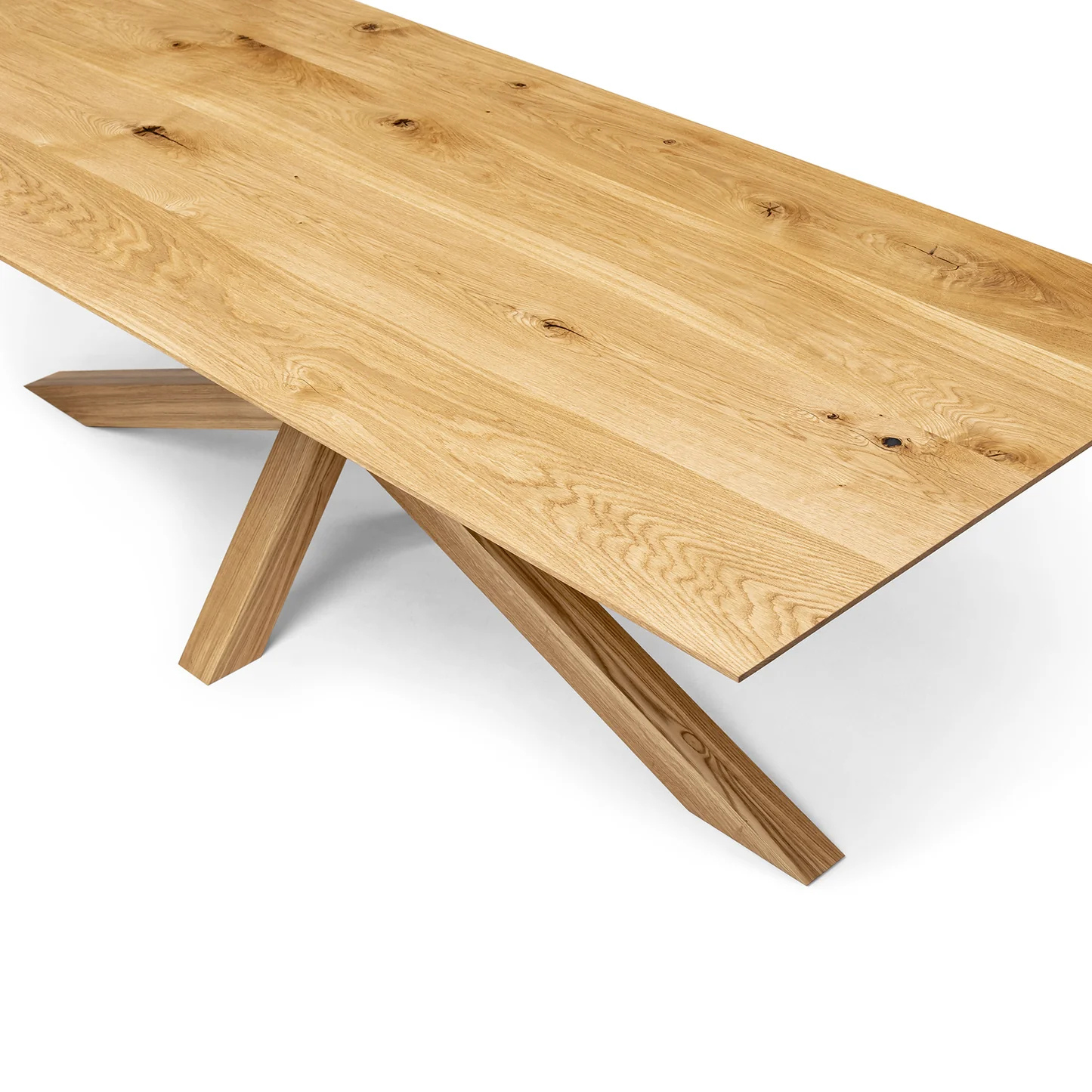 Elegant wooden dining table in natural oak with a bold spider leg frame.