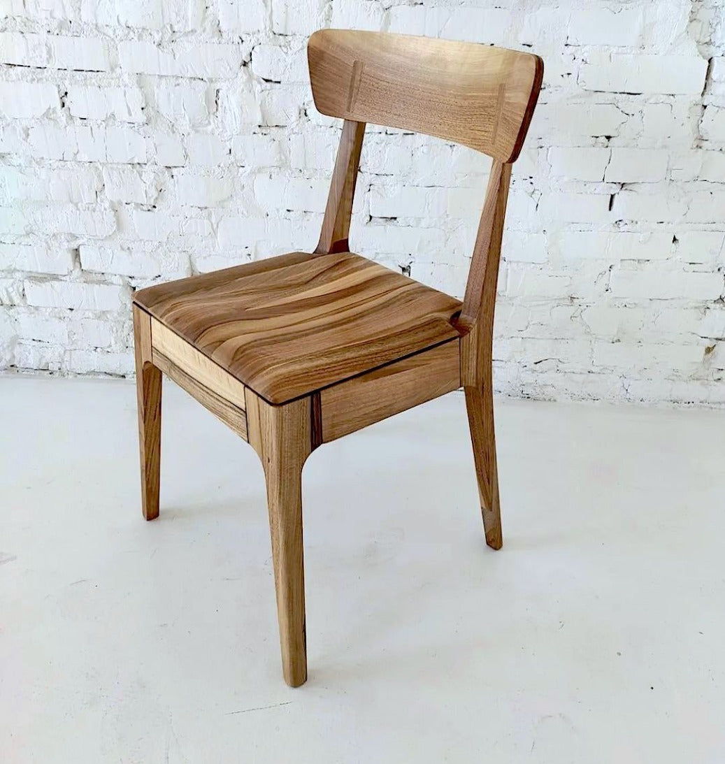 Minimalistic solid wood dining chair in natural walnut with a wood seat.