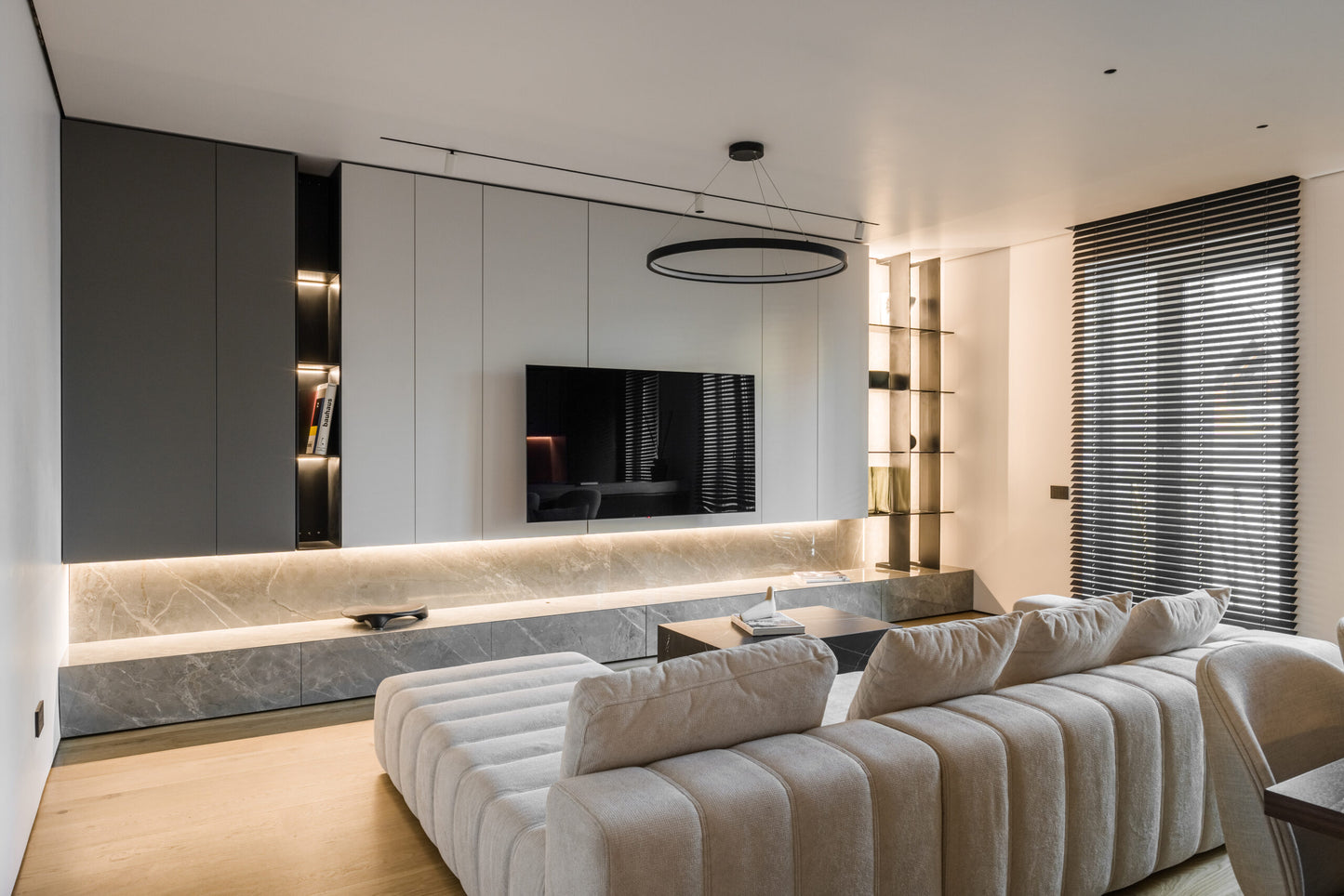 Modern living room with a beige luxury sofa, TV, and decorative elements.