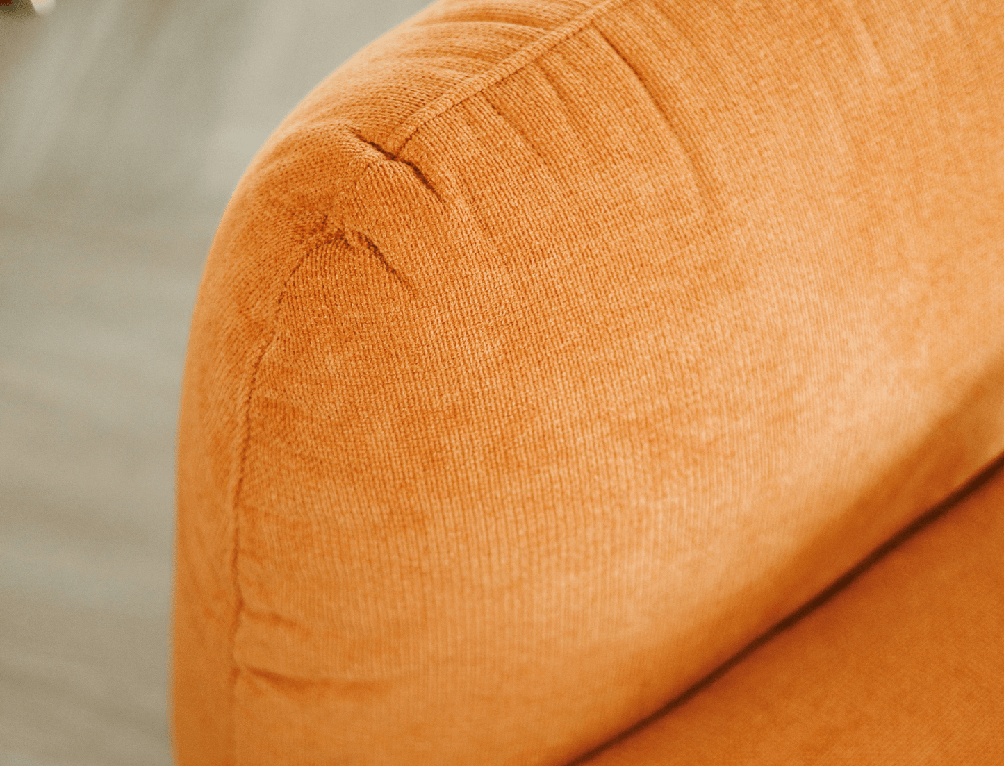 Contemporary armchair without armrests in textured orange fabric – a bold, modern touch.
