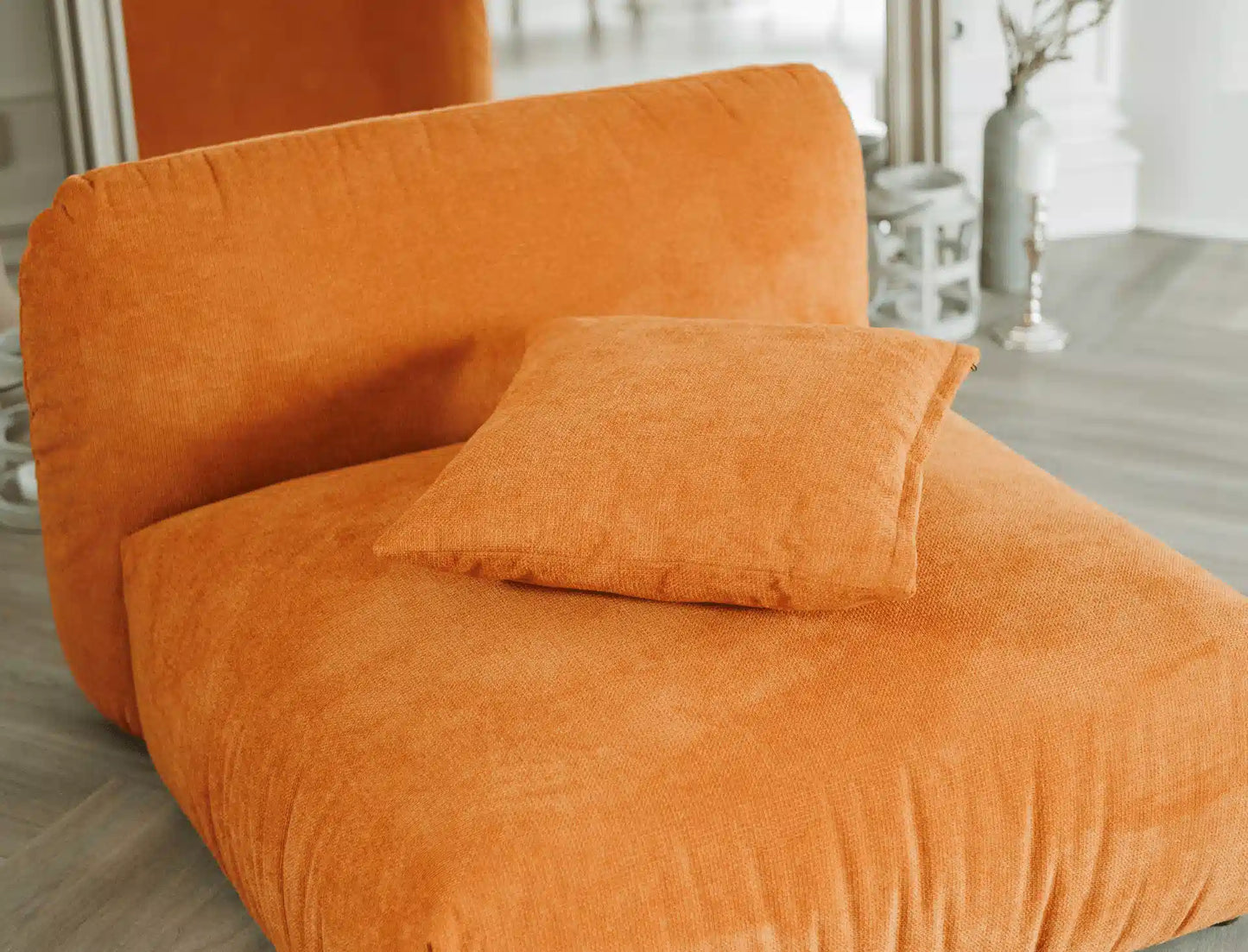 Orange armchair with a pillow in a room setting