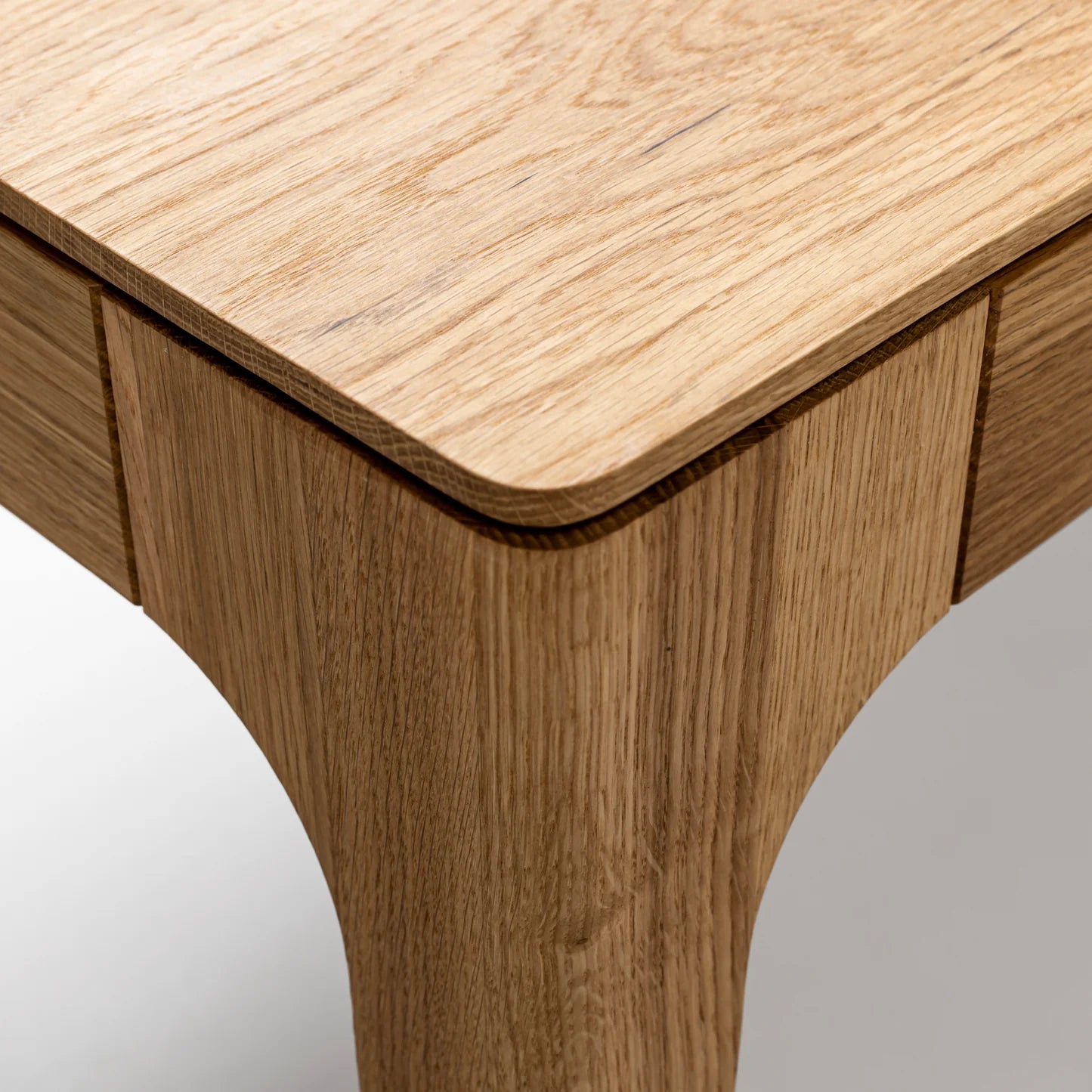 Rectangular solid wood dining table with hidden extension mechanism in natural oak.