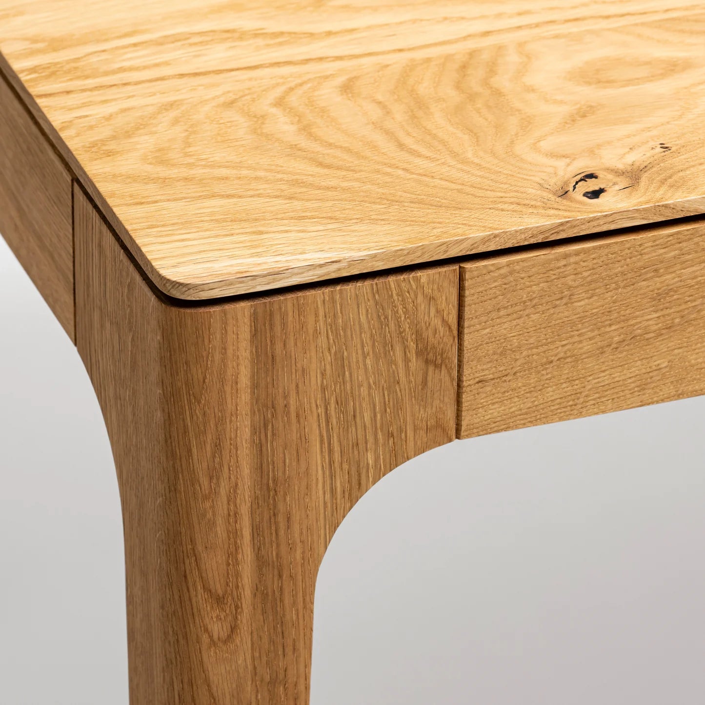 Rectangular solid wood dining table with hidden extension mechanism in natural oak.
