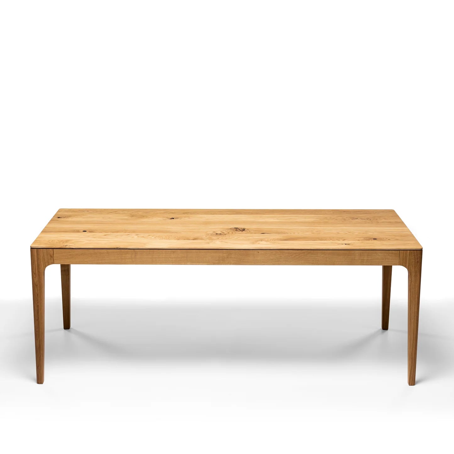 Rectangular solid wood dining table with hidden extension mechanism in natural oak.