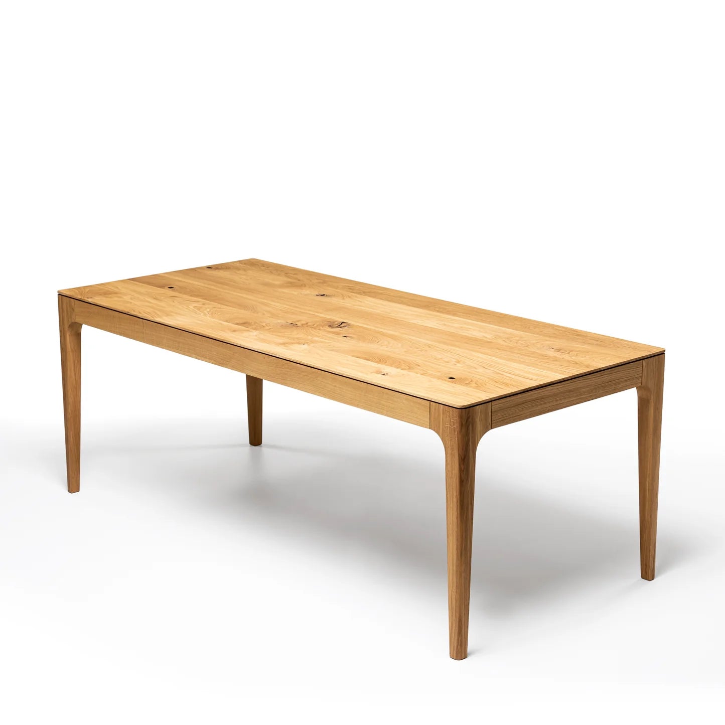 Rectangular solid wood dining table with hidden extension mechanism in natural oak.
