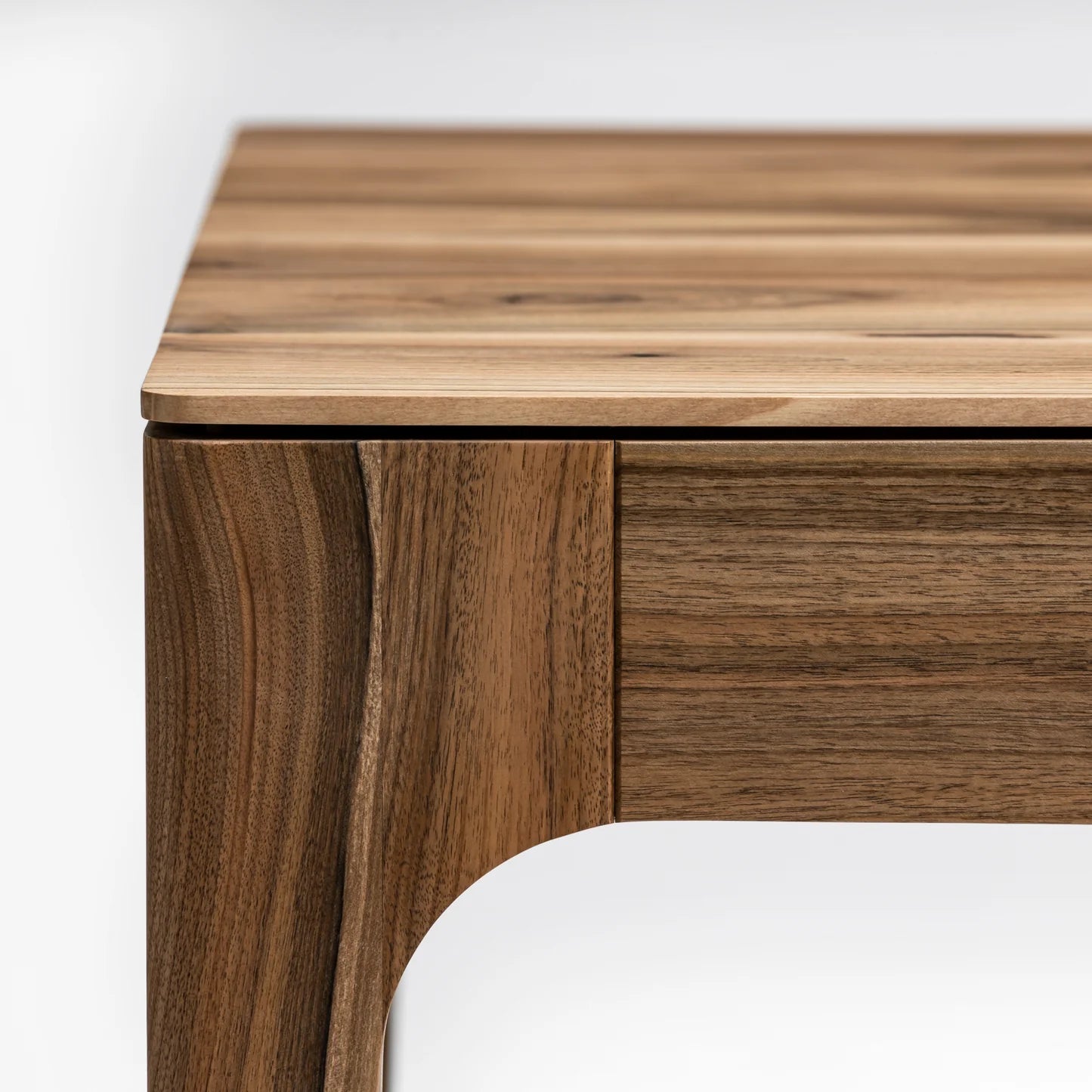 Rectangular solid wood dining table with hidden extension mechanism in natural walnut.