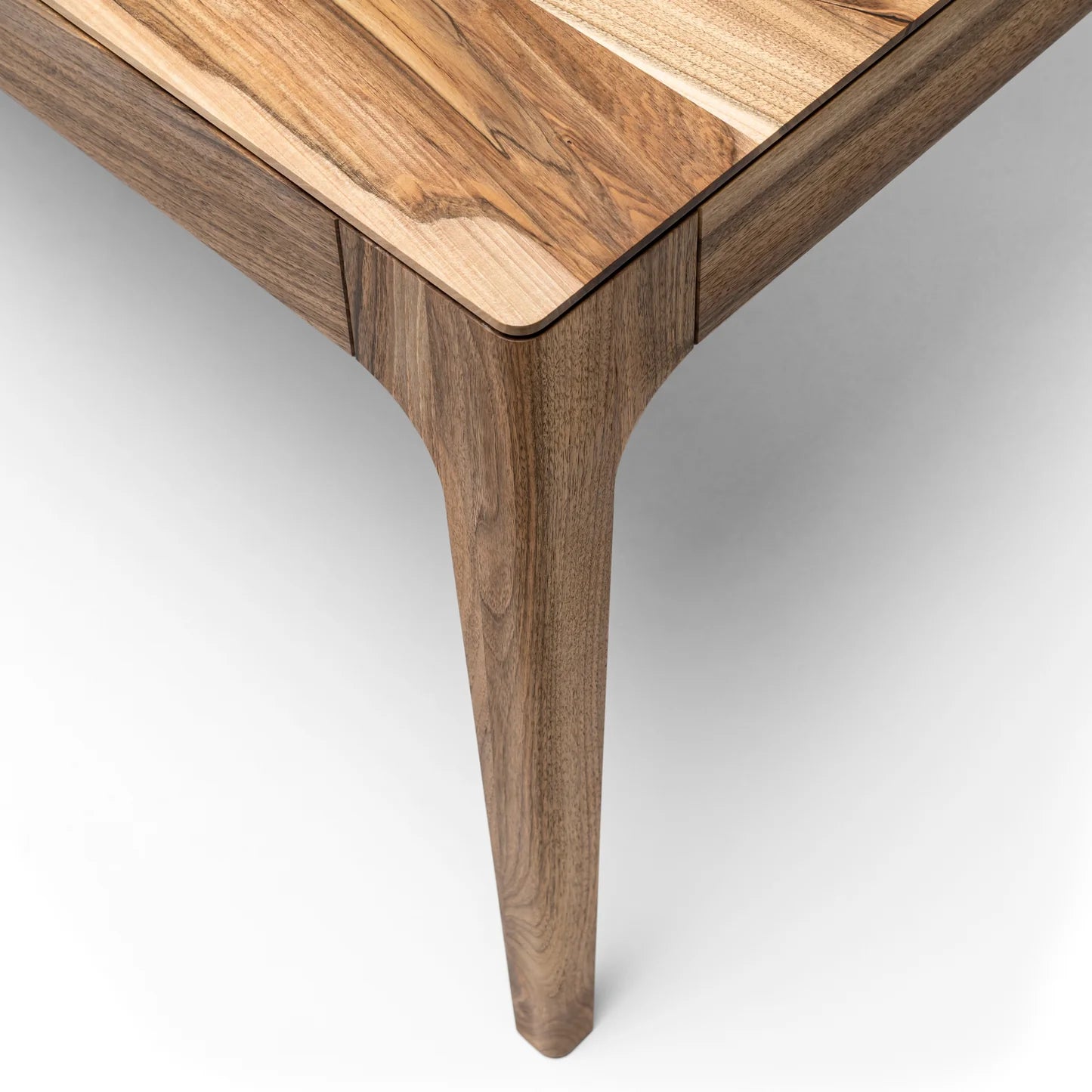 Rectangular solid wood dining table with hidden extension mechanism in natural walnut.