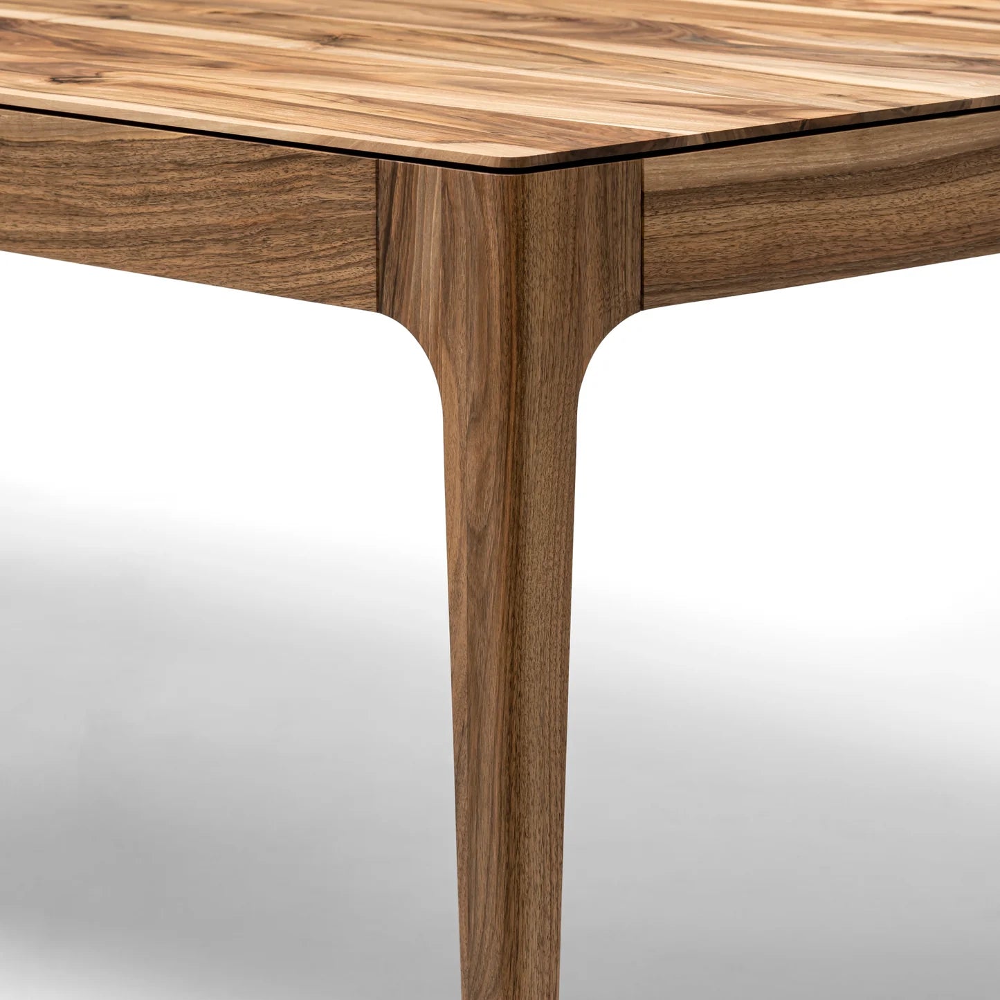 Rectangular solid wood dining table with hidden extension mechanism in natural walnut.