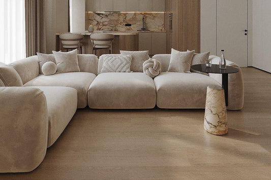 Divano angolare modulare in velluto beige in un soggiorno moderno ed elegante, con accenti beige e tavolino da caffè in pietra.