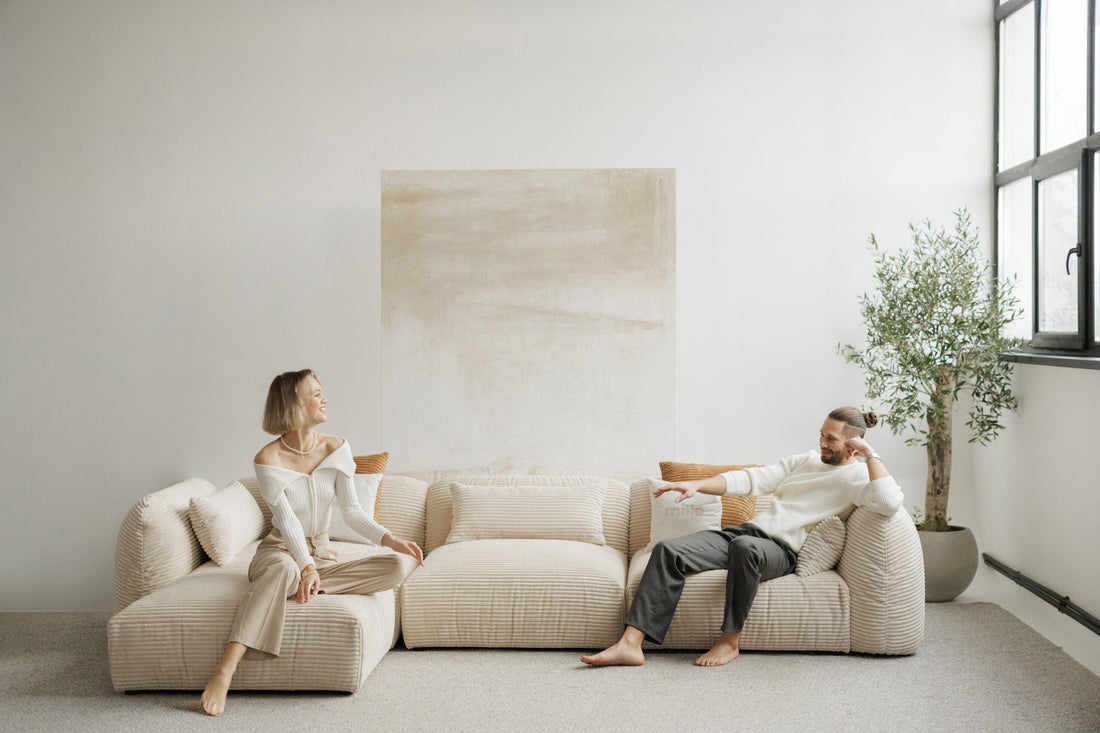 White corduroy modular sofa in a studio with man and woman sitting on it. 