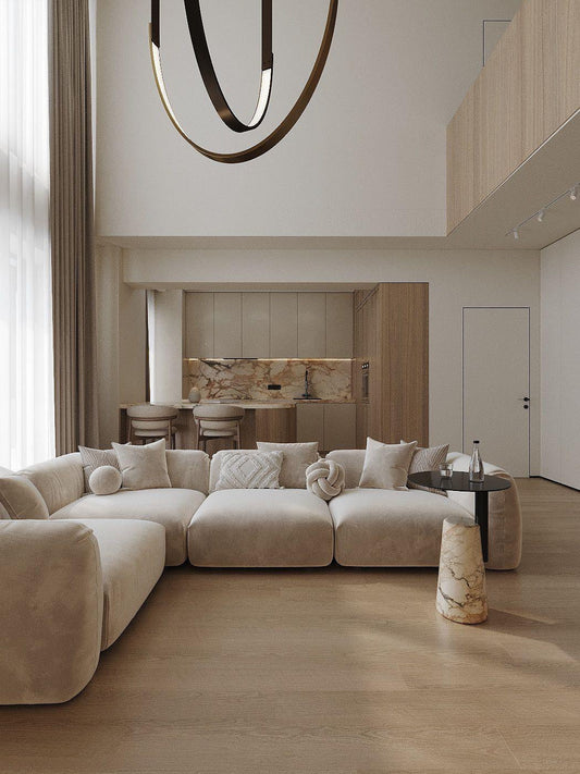 Modern luxury beige modular sofa in L shape with stylish pillows in an elegant living room with kitchen and bar table in the back. 