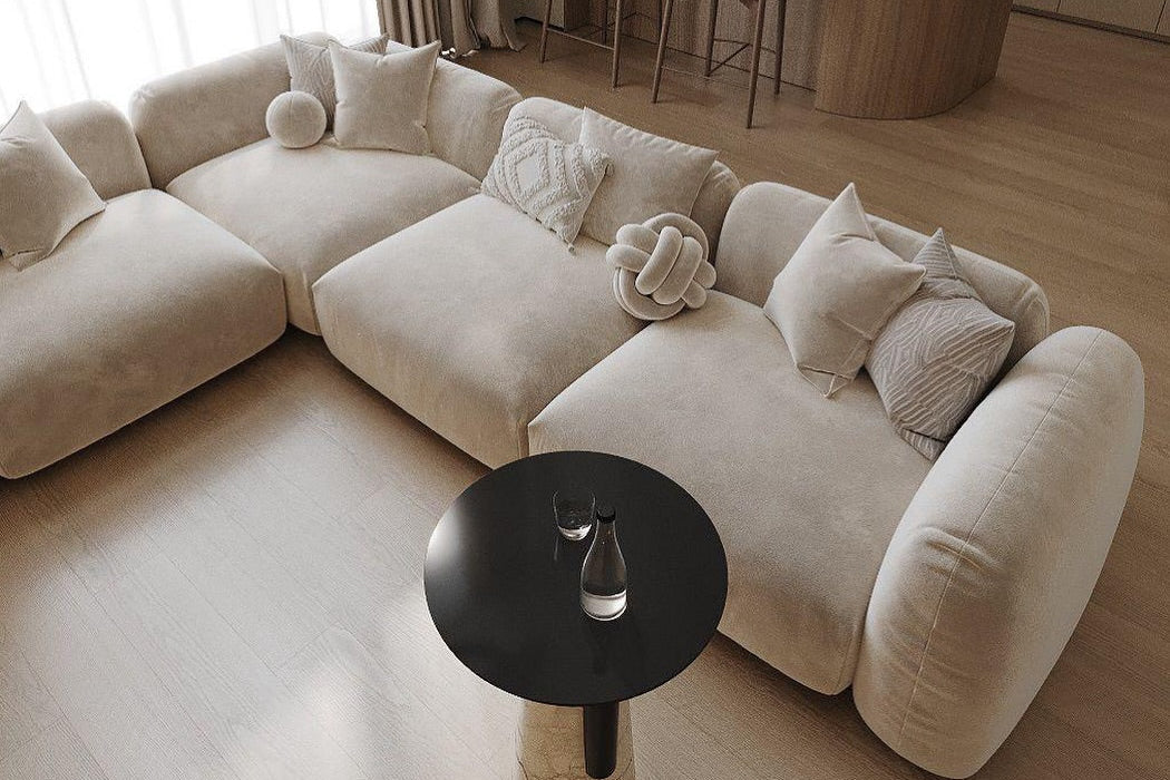 Beige velvet sectional sofa with decorative pillows in a modern living room setting.