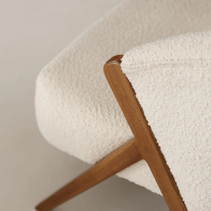 Modern white bouclé armchair with wooden arms. 