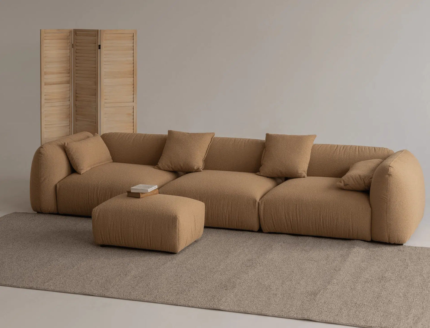 Brown boucle luxury sofa in a minimalistic studio room with matching ottoman. 