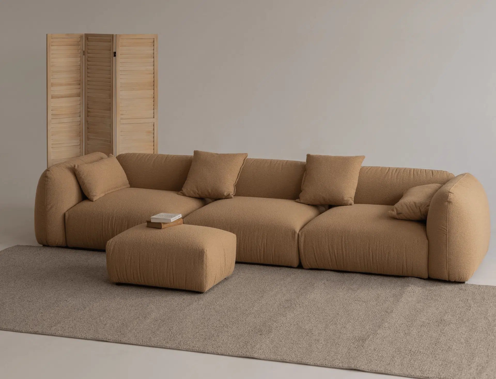 Brown boucle luxury sofa in a minimalistic studio room with matching ottoman. 