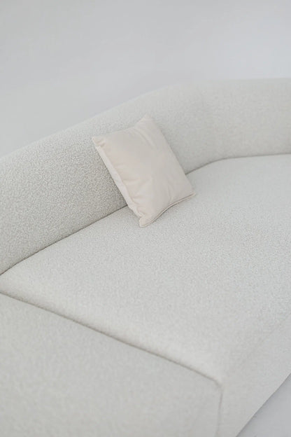 White boucle sofa with a pillow on a white background
