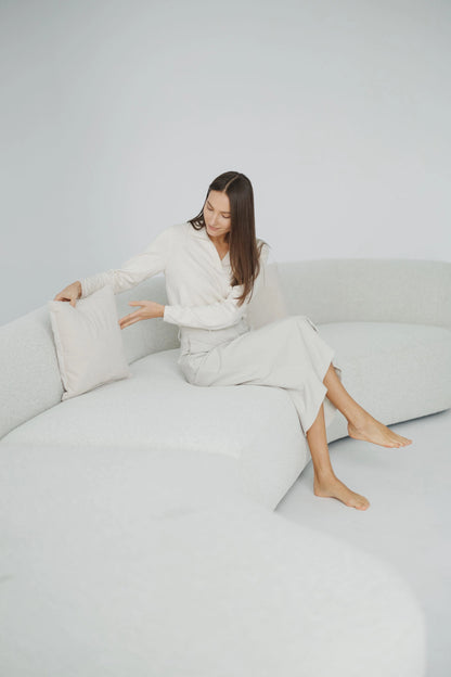 Woman sitting on a white boucle sofas couch with a white pillow.