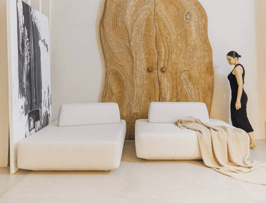 Modern designer living room with white minimal sofa, wooden door, and a woman in a black dress.