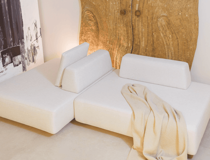 White sectional sofa with a beige blanket against a wooden door.