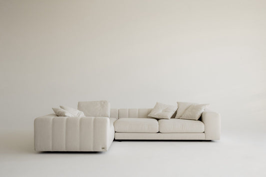 Elegant beige sectional sofa with cushions on a white background