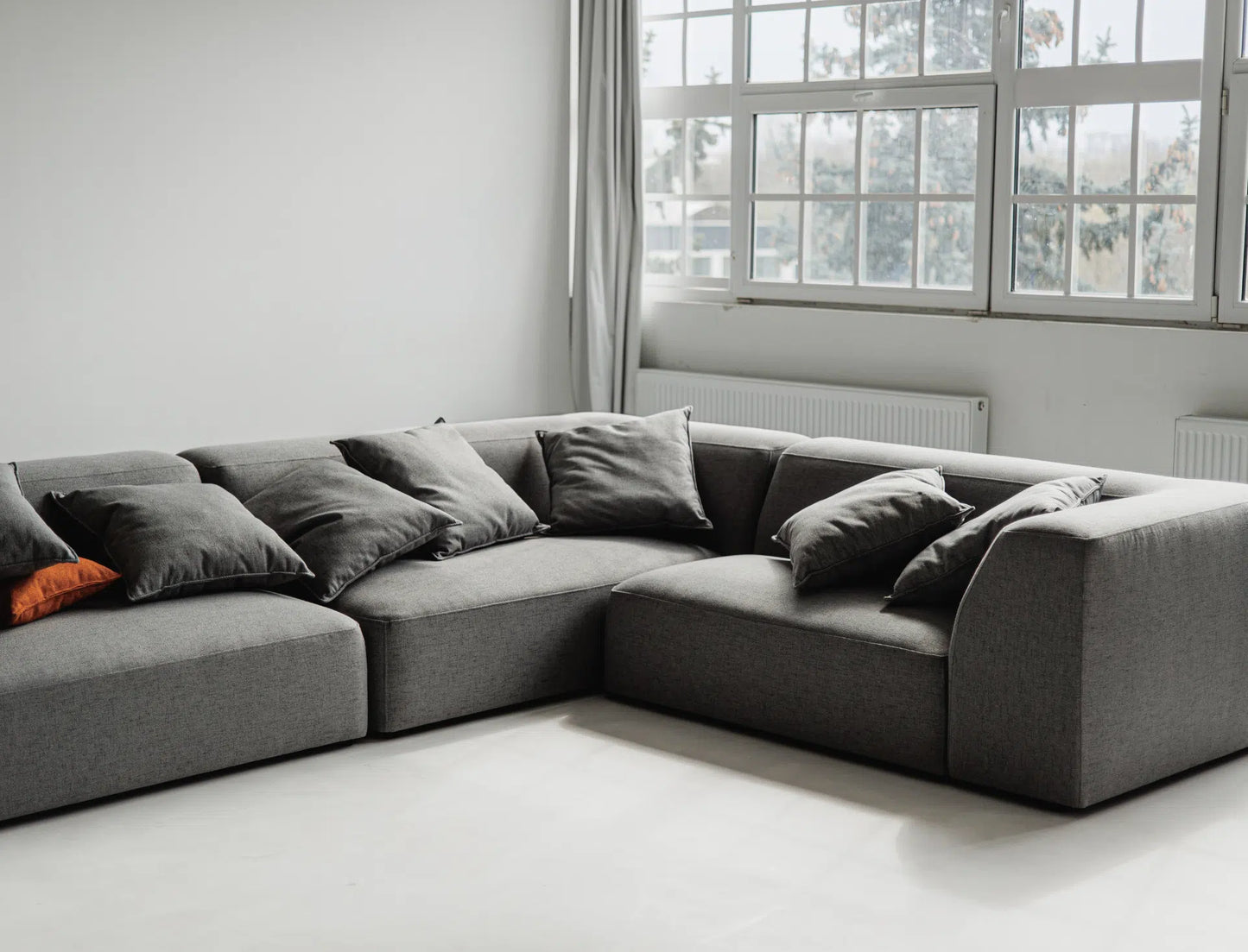 Gray sectional sofa in a room with large windows.