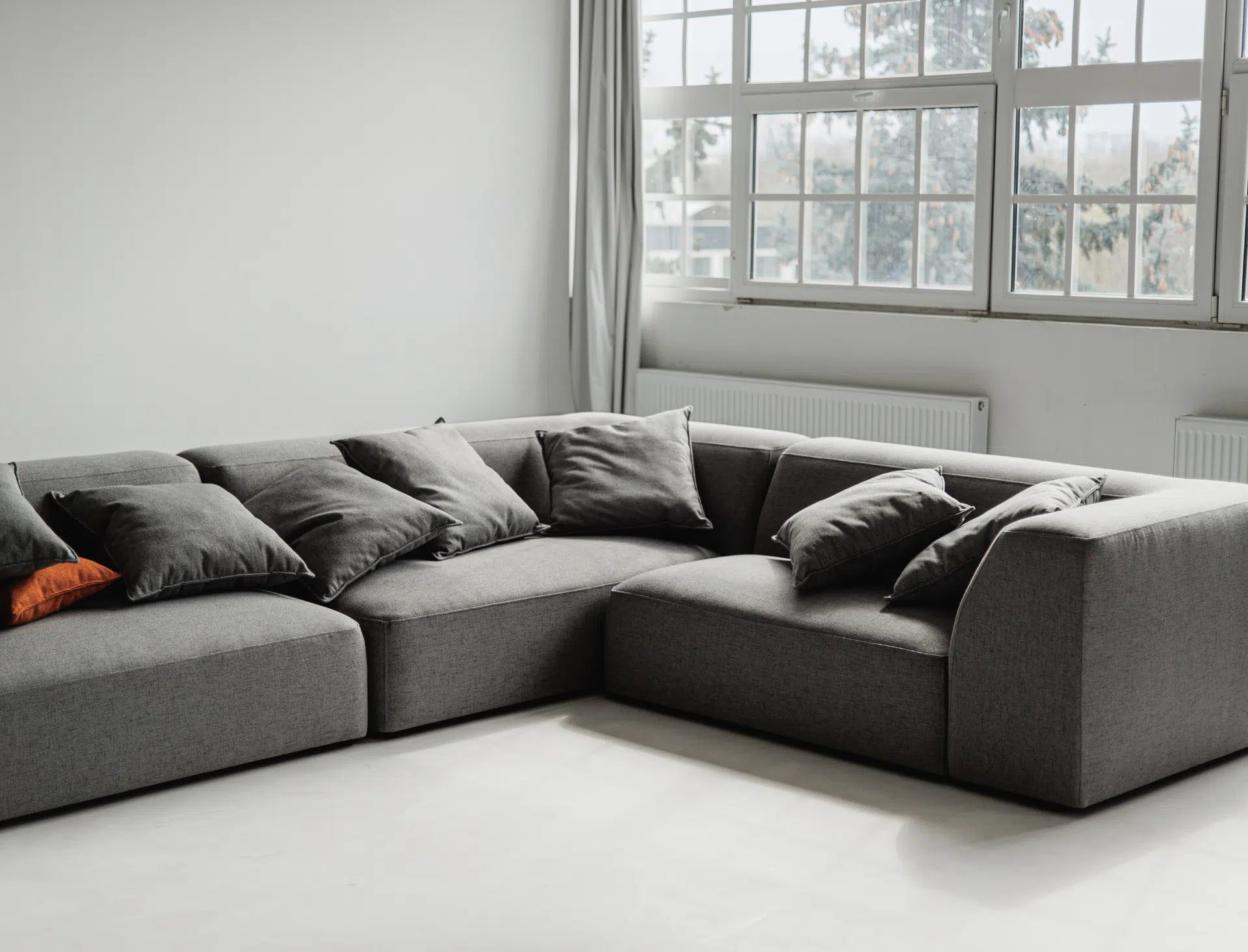Gray sectional sofa in a room with large windows.