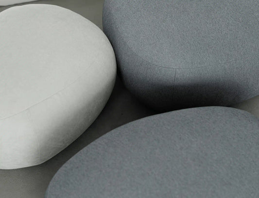 Three gray ottomans of different shades on a neutral background