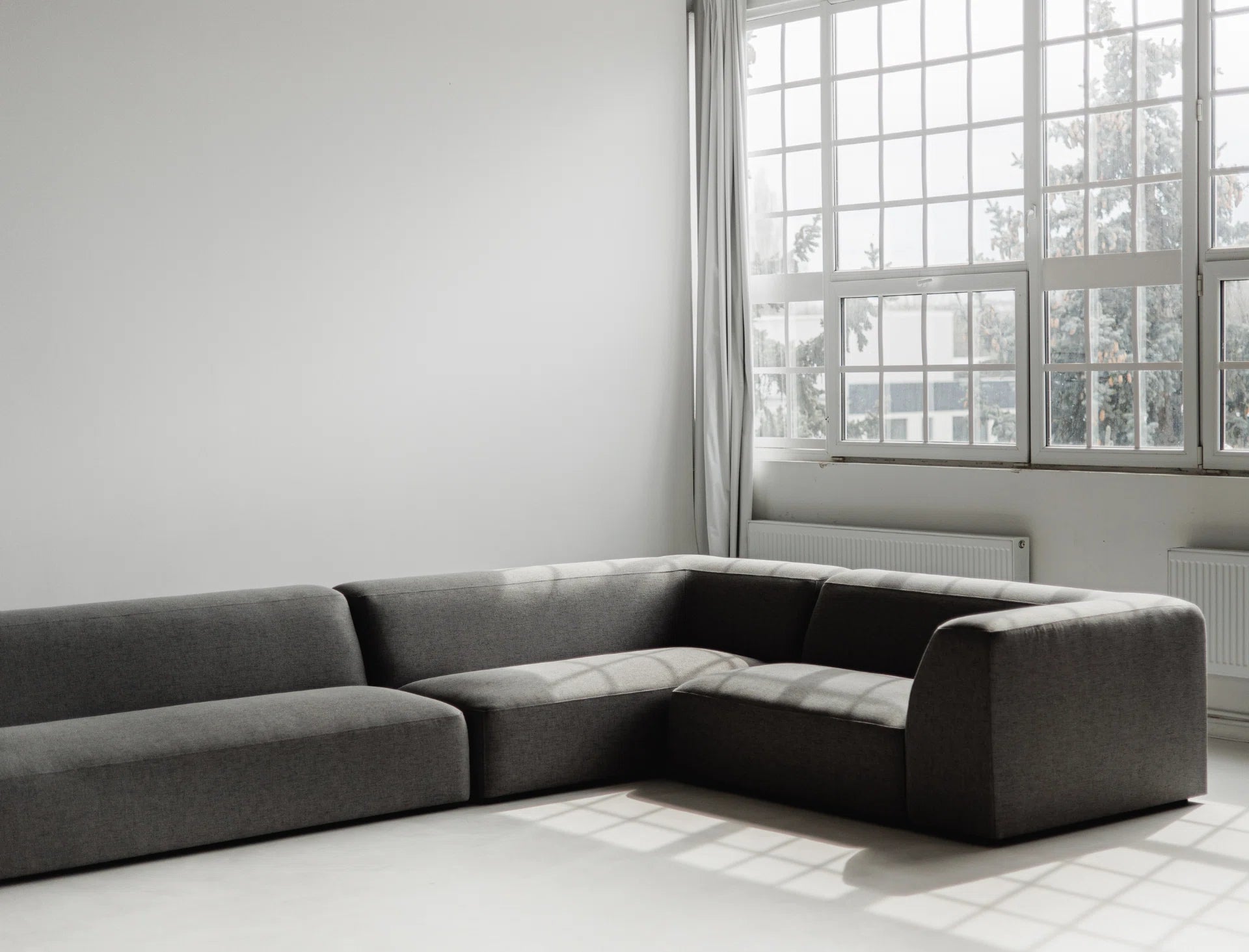 Gray sectional sofa in a room with large windows