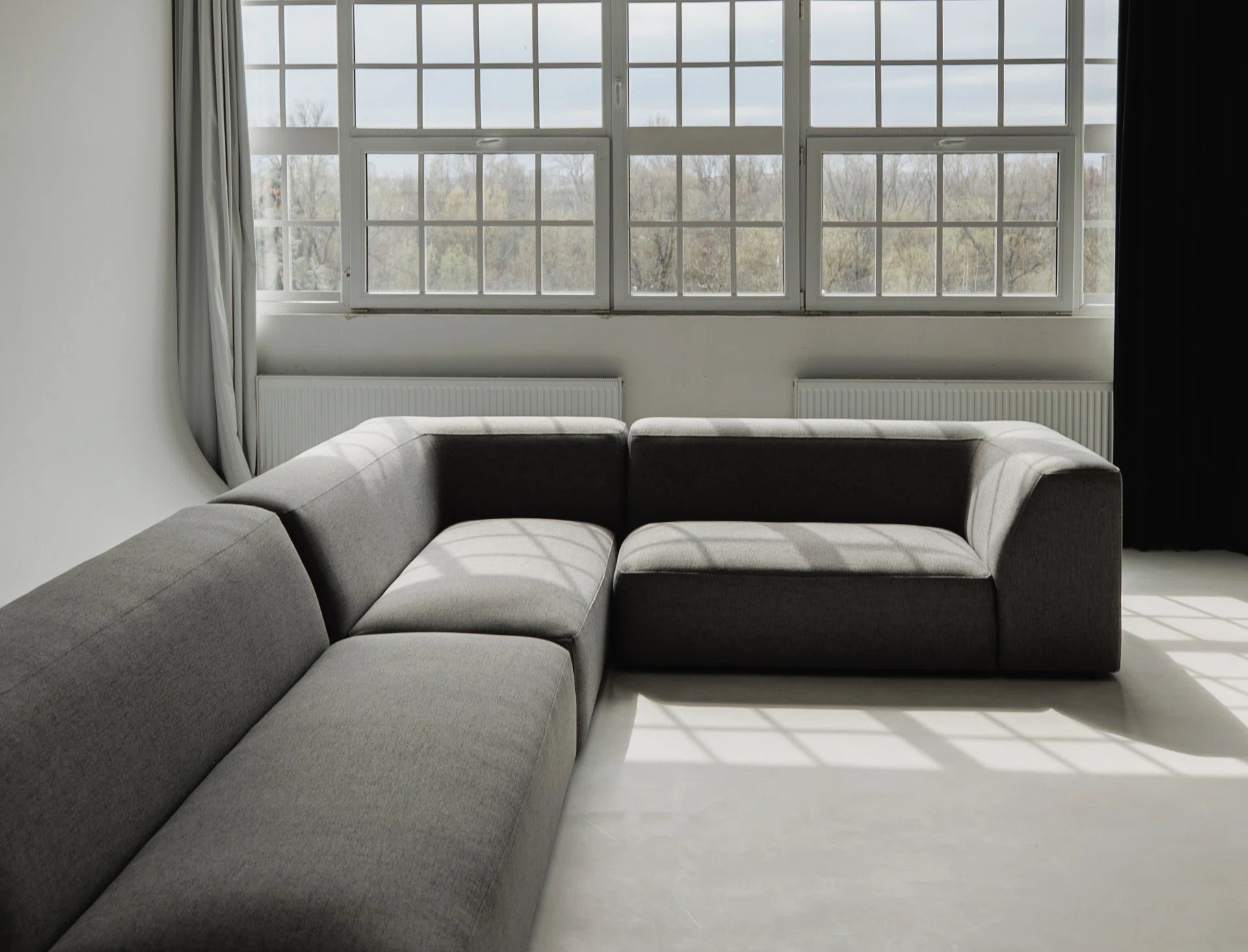 Gray sectional sofa in a room with large windows.