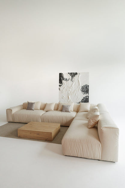 Beige sectional sofa in a minimalistic living room with a abstract painting on the wall.