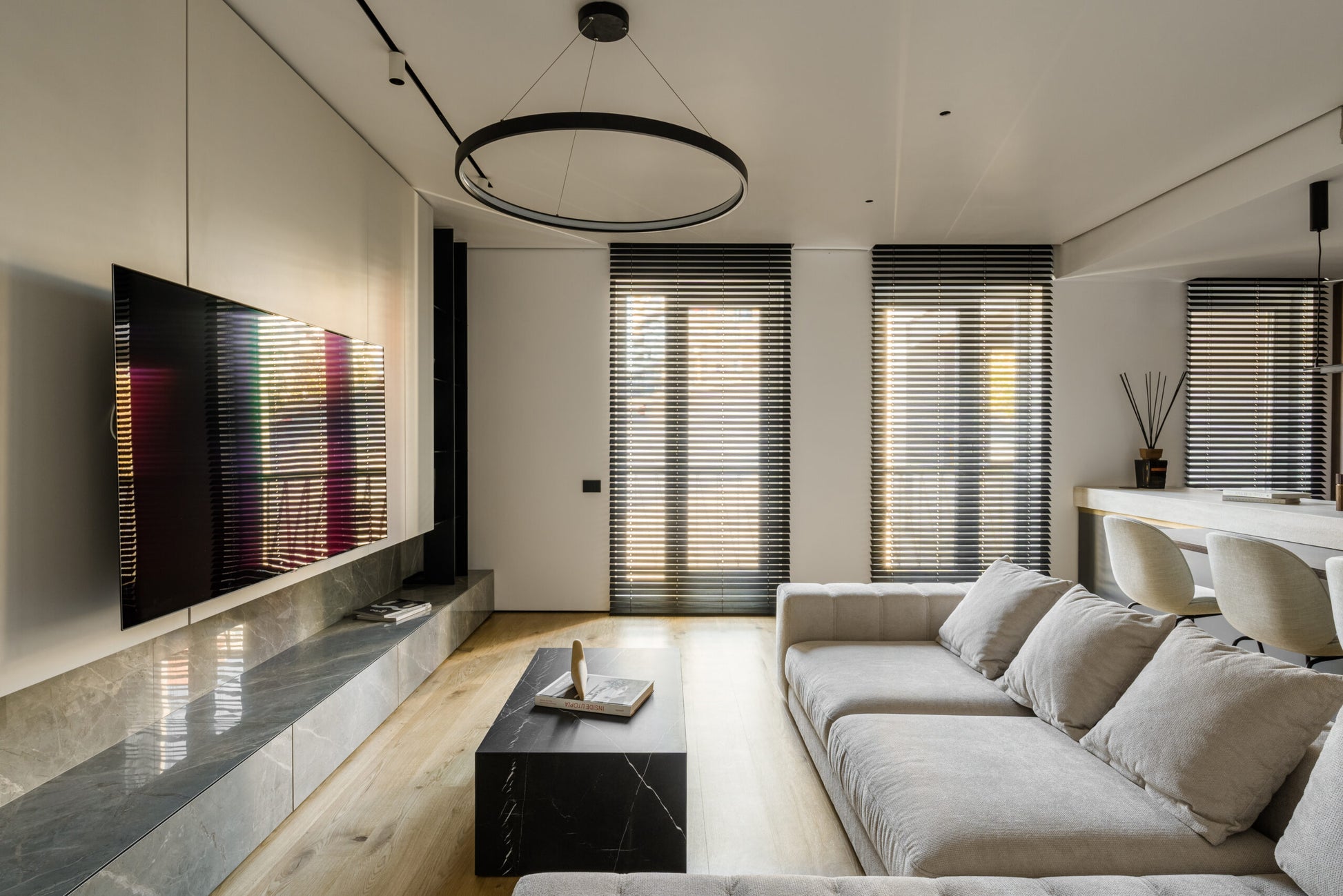 Modern living room with a beige luxury sofa, coffee table, and wall-mounted TV.