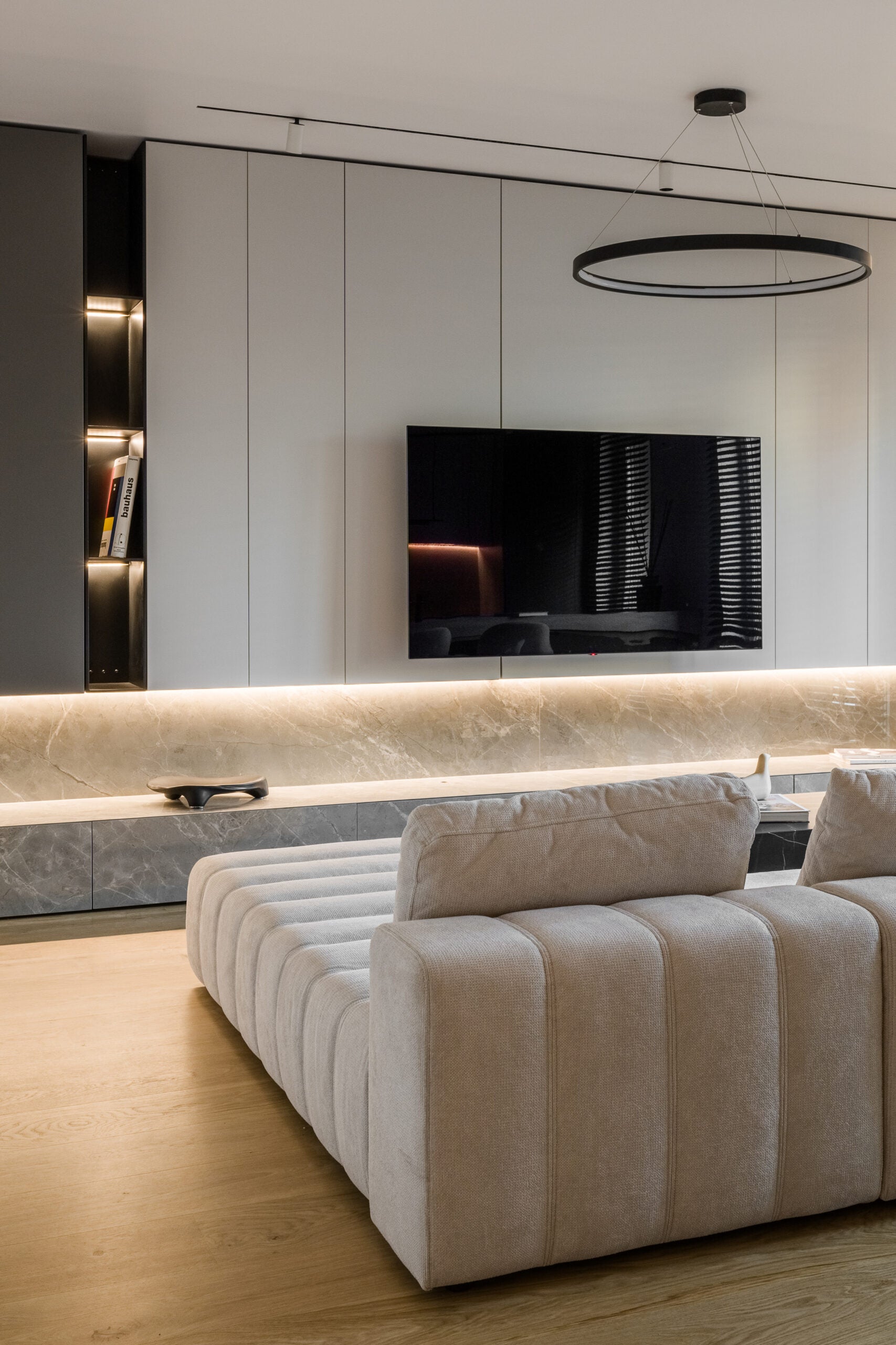 Modern living room with a beige modular sofa and a television mounted on a wall.
