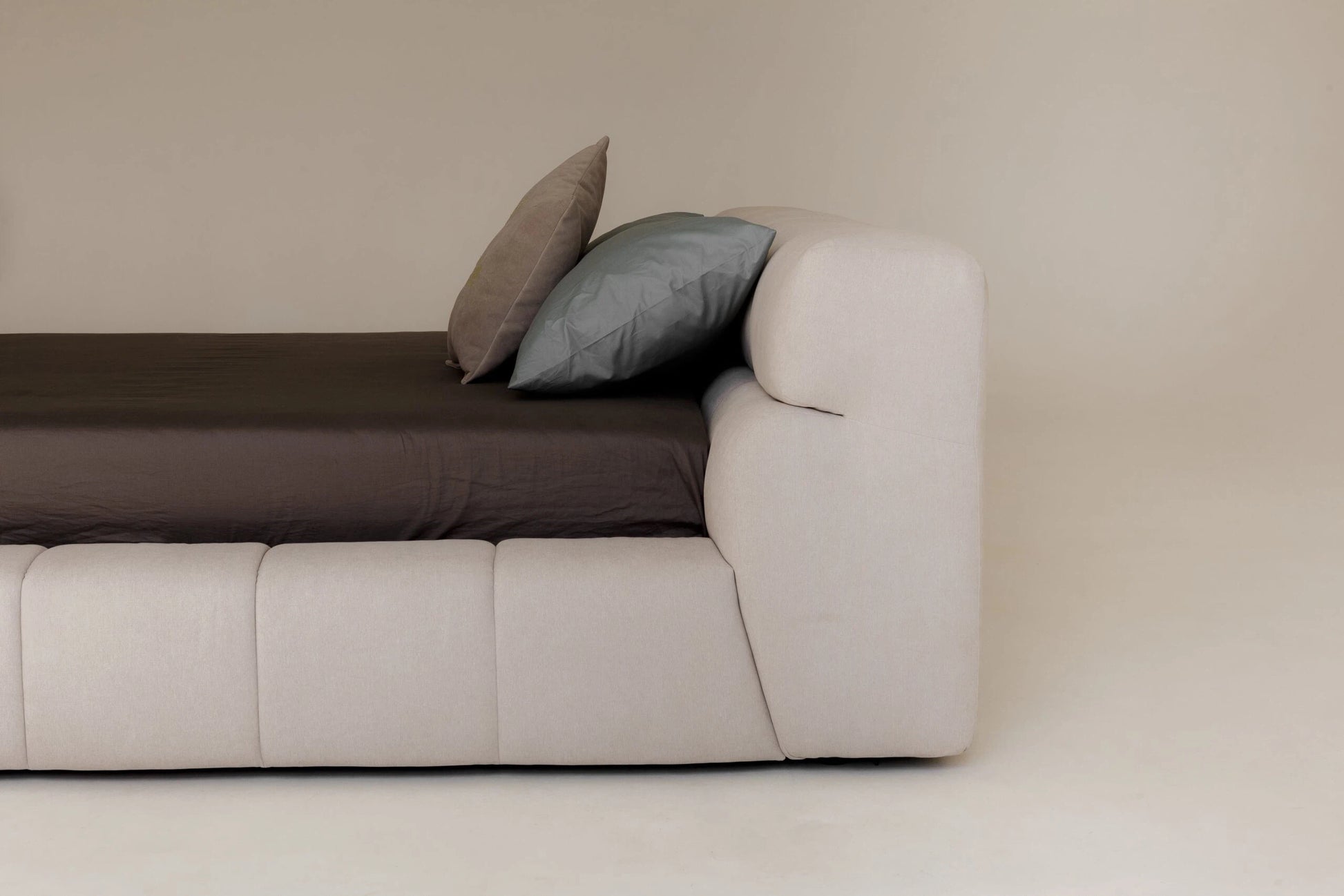 Modern upholstered bed with two cushions on a plain background