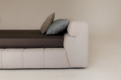 Modern upholstered bed with two cushions on a plain background