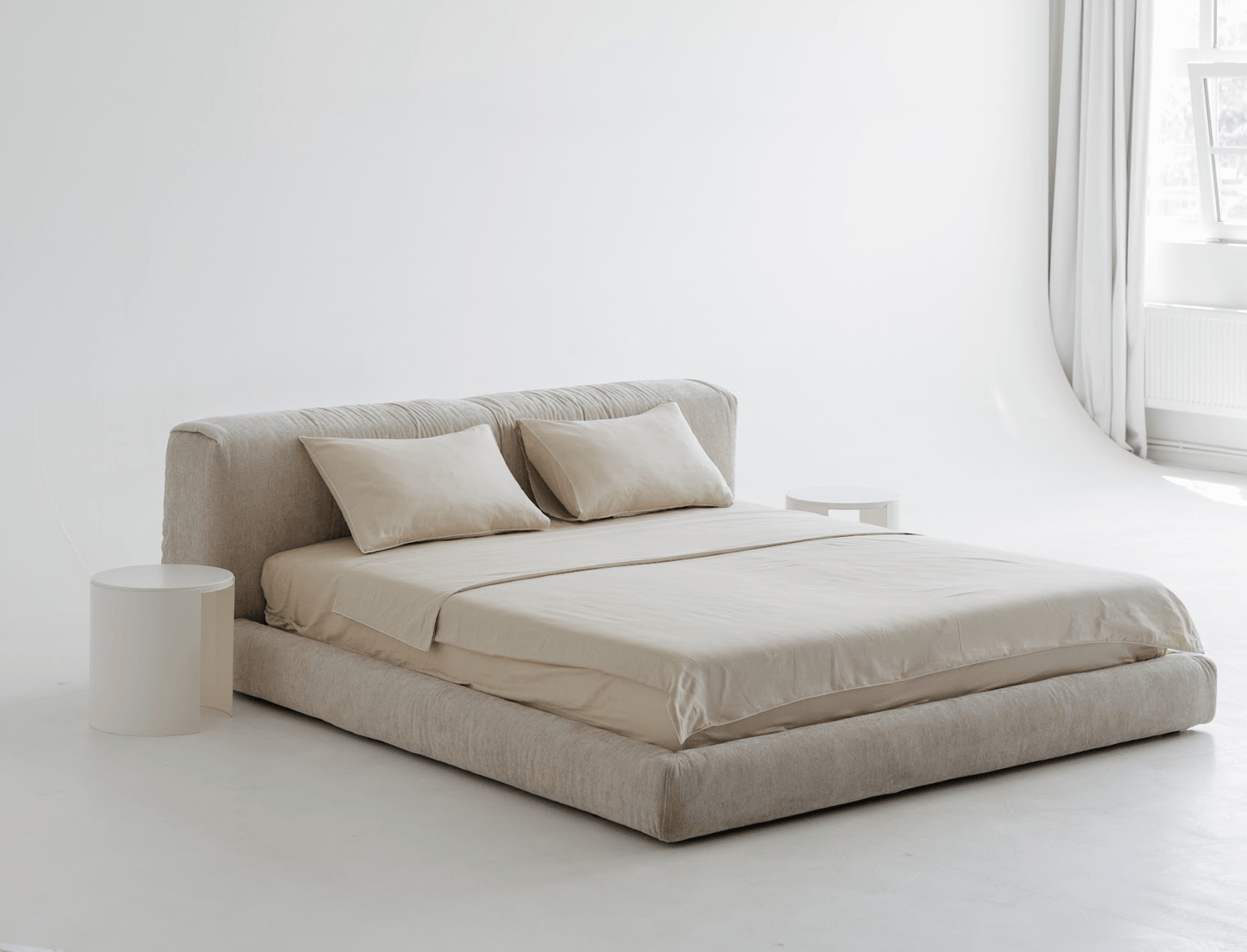 Beige upholstered bed with pillows in a minimalistic room