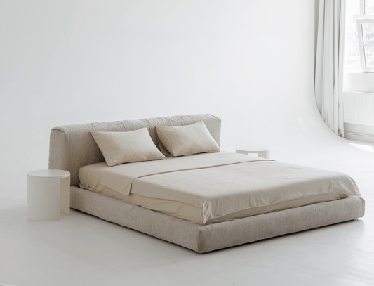 Beige upholstered bed with pillows in a minimalistic room