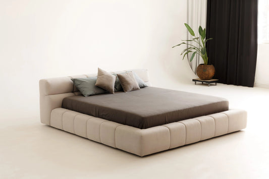 Modern platform bed with beige frame and brown mattress in a minimalistic room.