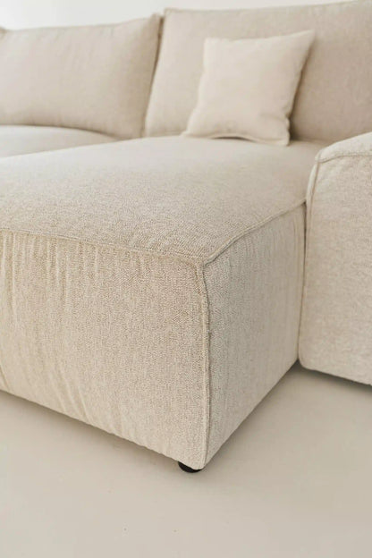 Beige sectional sofa bed with a pillow on a light beige background