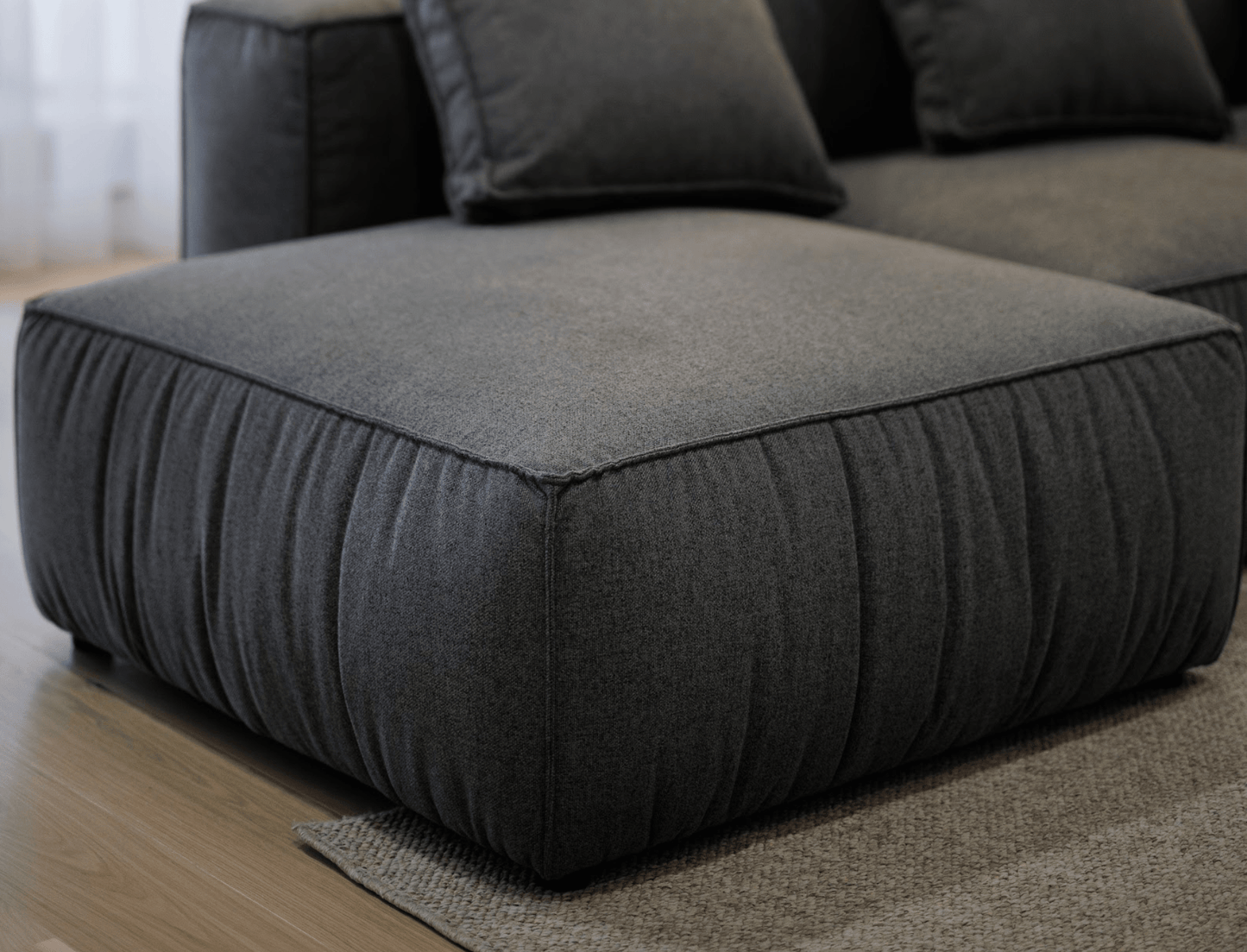 Black fabric ottoman sofa  on a wooden floor