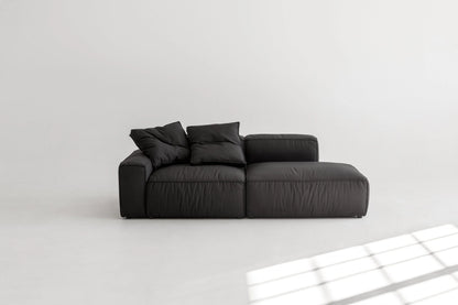 Black modular sofa on a white floor with a light gray wall