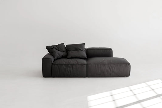 Black modular sofa on a white floor with a light gray wall