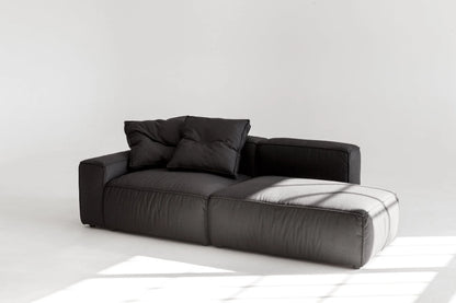 Black modular sofa with cushions on a white floor and background