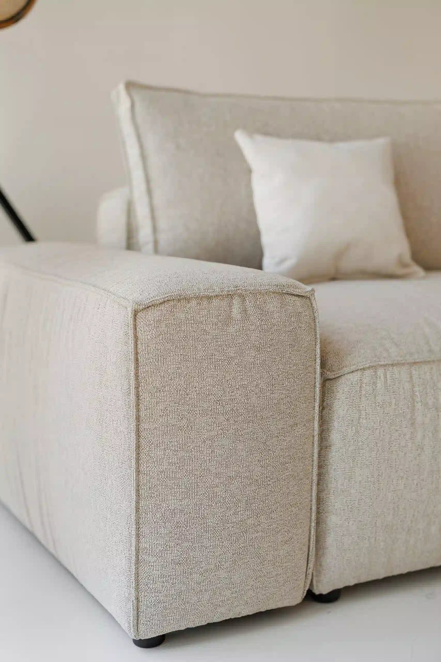 Beige modular sofa with a textured armrest on a white background