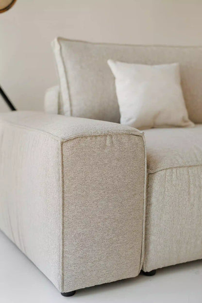 Beige modular sofa with a textured armrest on a white background