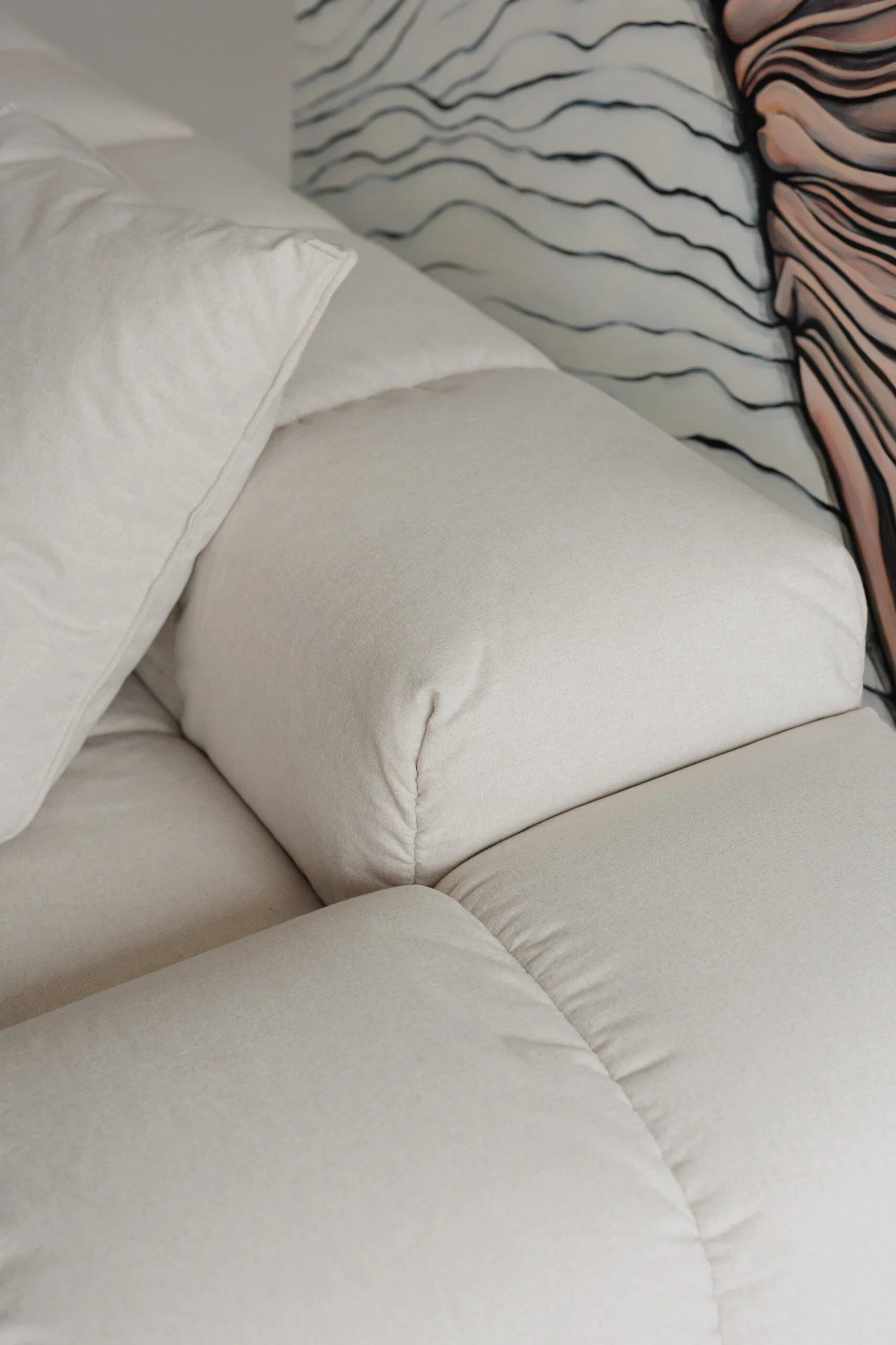 Close-up of a beige sofa with cushions against a neutral background