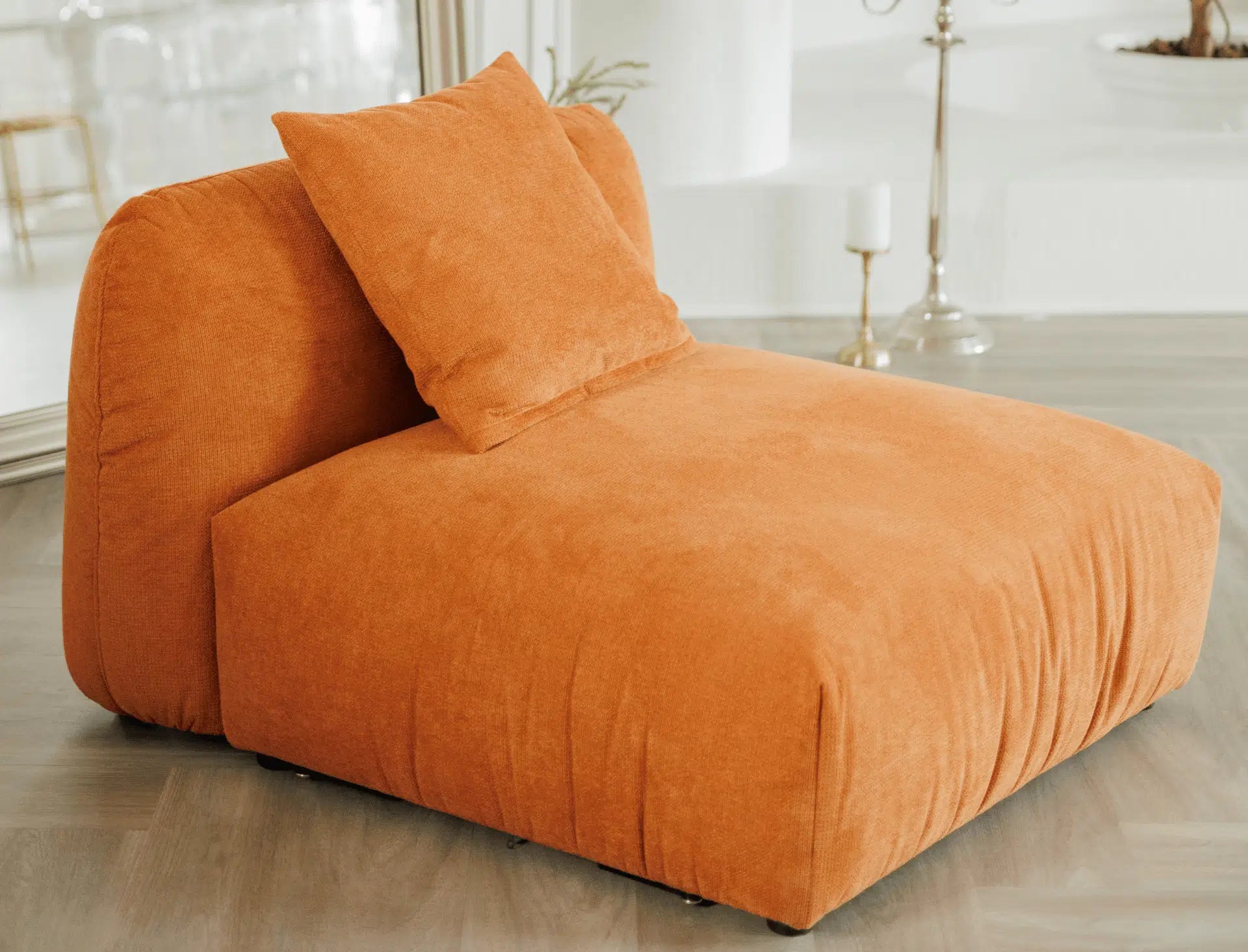 Orange modular armchair chair with cushions on a wooden floor.