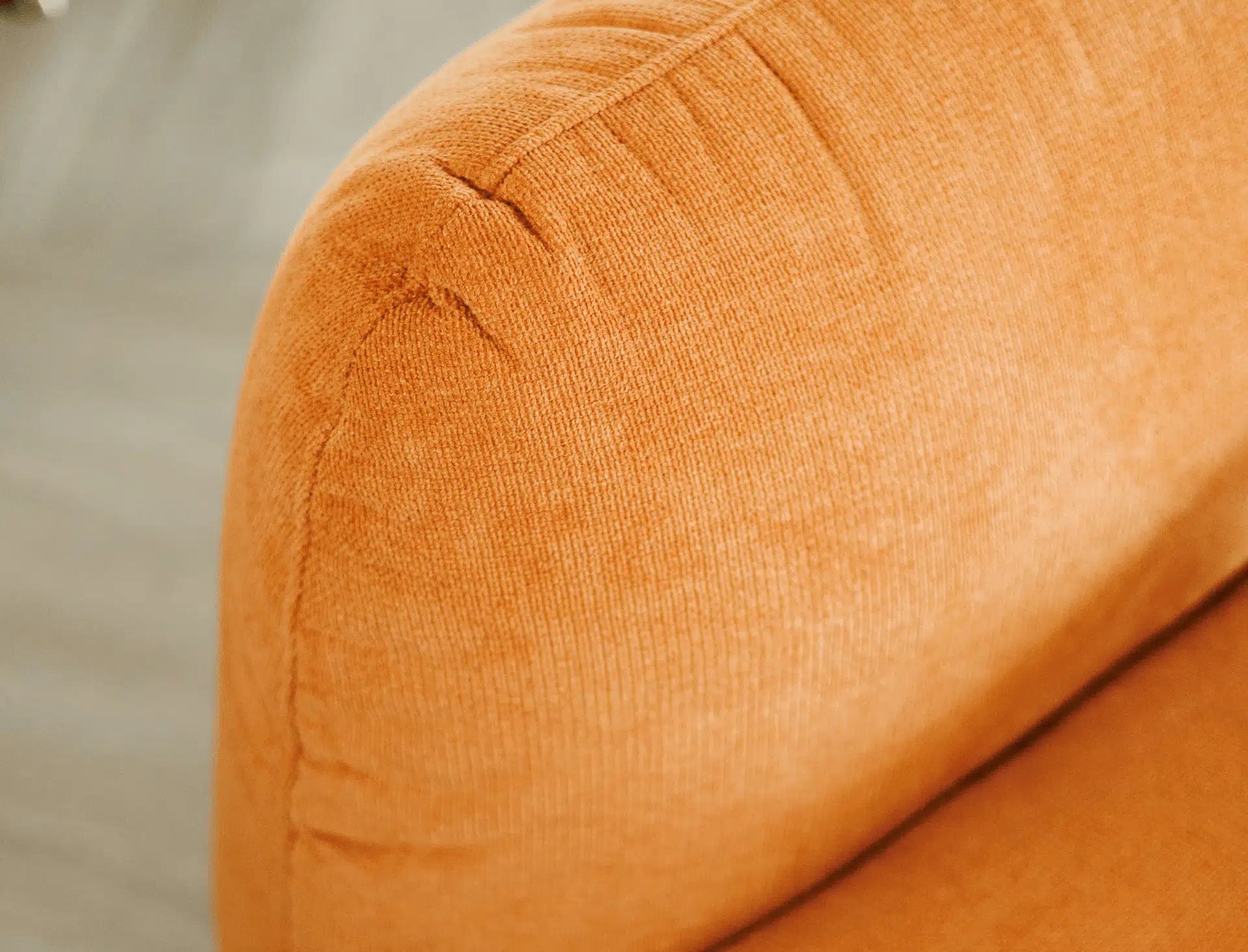Close-up of a textured orange armchair on a neutral background