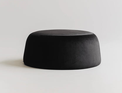 Round black velvet ottoman on a light gray background.